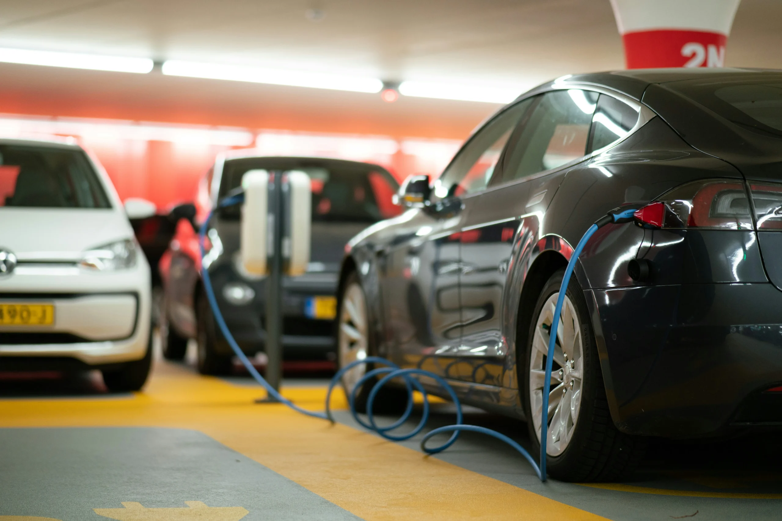 A black car & a white car being charged in public parking area